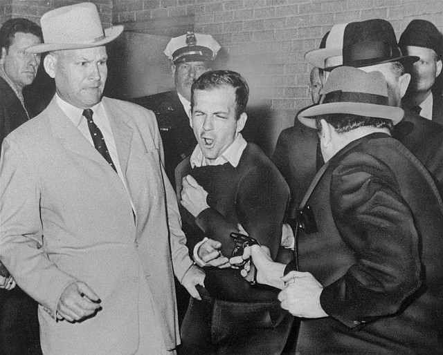 In this Nov. 24, 1963 file photo, Lee Harvey Oswald reacts as Dallas night club owner Jack Ruby, foreground, shoots at him from point blank range in a corridor of Dallas police headquarters. At left is Detective Jim Leavelle. The longtime Dallas lawman who was captured in one of history's most iconic photographs as he escorted President John F. Kennedy's assassin moments before he was fatally shot, died Thursday. He was 99.